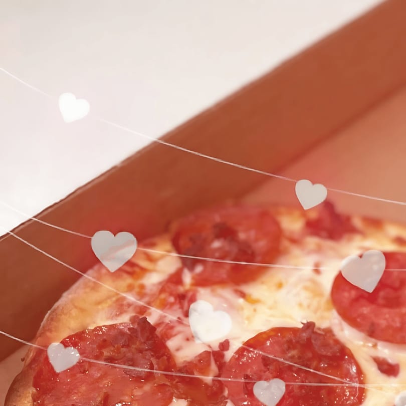 Pepperoni pizza in a delivery box, adorned with white heart-shaped lights.