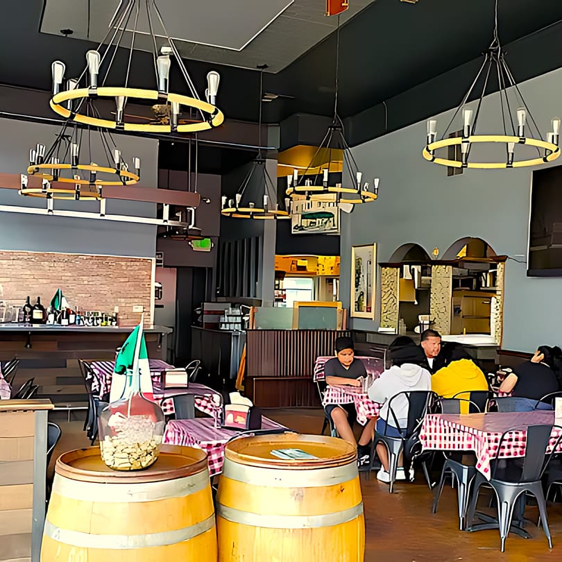 Interior of North Beach Pizza with checkered tablecloths, wine barrels, and patrons dining.