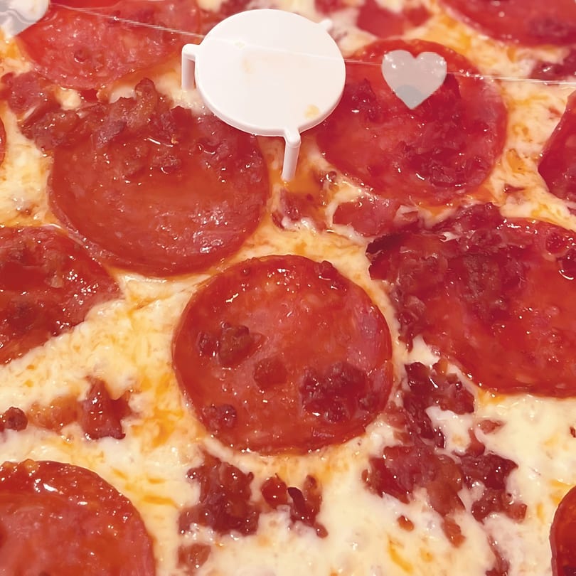 Close-up of a North Beach Pizza pepperoni pizza with a white plastic pizza saver and heart.