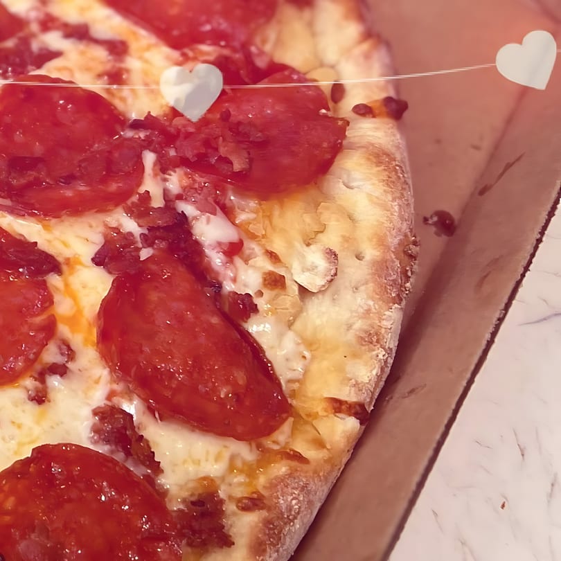 Close-up of a North Beach Pizza pepperoni pizza with melted cheese in a delivery box.